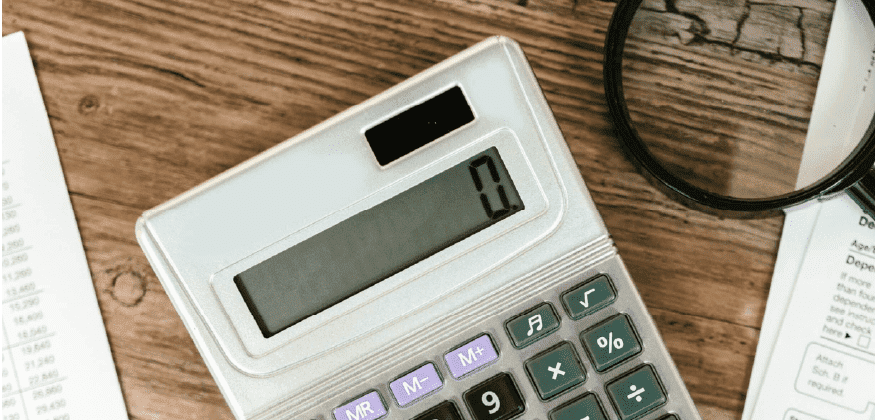 Une calculatrice posée sur une table à côté d'une loupe.