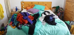 Un lit en désordre avec des vêtements éparpillés partout