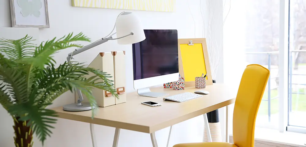 Bureau en bois sur lequel est posé un ordinateur, de la décorations et des rangements